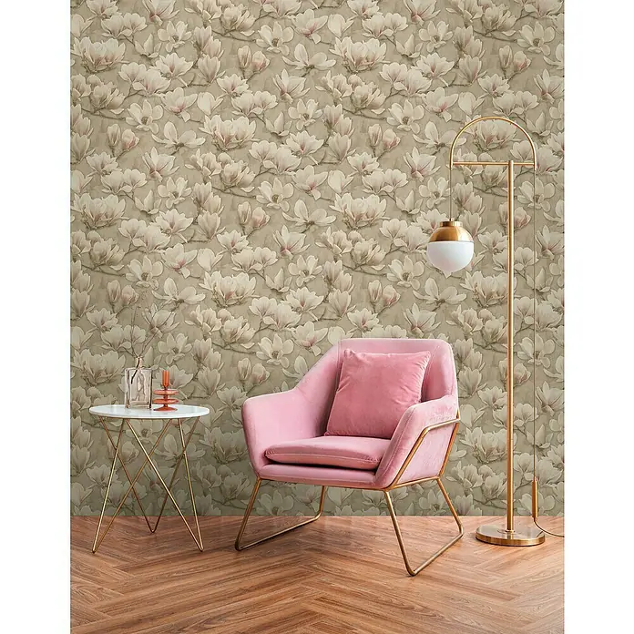 A.S. Création Pintwalls 2 Vliestapete Magnolien - Braun-Rosa-Weiß, Floral, 10,05 x 0,53 m - Dieser Raum zeigt einen rosa Sessel mit goldenem Gestell, eine Lampe und einen Tisch vor einer Tapete mit Magnolienmuster.
