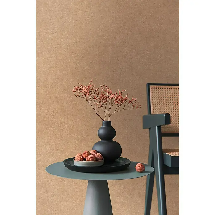 A.S. Création Metropolitan Stories Hot Spots Vliestapete - Braun-Orange, Uni, 10,05 x 0,53 m - Stilleben mit einer schwarzen Vase mit Trockenblumen, einer Schale mit Litschis und einem blauen Stuhl auf einem Tisch.