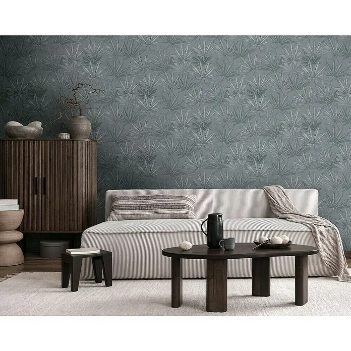 A.S. Création Michalsky Metropolis Vliestapete Hanfblätter - Grau, Floral, 10,05 x 0,53 m - Wohnzimmer mit Sofa vor gemusterter Tapete, dunklem Schrank und Tisch. Gemütliche Atmosphäre mit dekorativen Elementen.