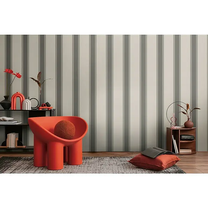 A.S. Création Michalsky Metropolis Vliestapete - Beige-Grau, Streifen, 10,05 x 0,53 m - Einrichtungsidee mit orangefarbenem Sessel und dekorativen Elementen vor gestreifter Tapete, die eine stilvolle und moderne Atmosphäre schafft.