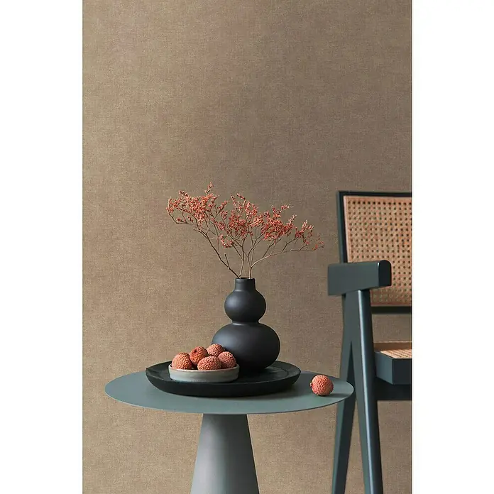 A.S. Création Metropolitan Stories Hot Spots Vliestapete - Braun, Uni, 10,05 x 0,53 m - Ein stilvolles Arrangement mit einer schwarzen Vase, Trockenblumen und einer Schale mit Litschis auf einem eleganten, runden Tisch.