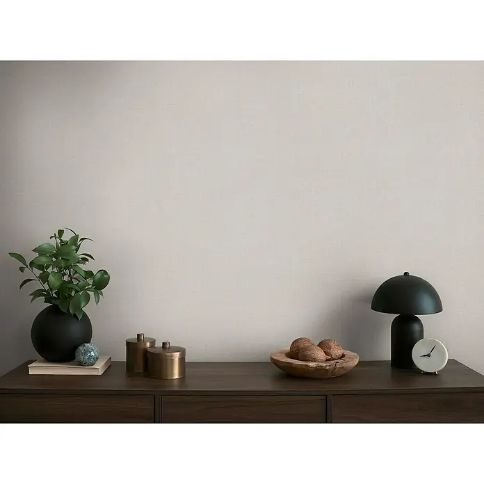 A.S. Création Michalsky Metropolis Vliestapete - Grau-Beige, Uni, 10,05 x 0,53 m - Schlichte Wohnraumdekoration mit einer stilvollen schwarzen Lampe, einer grünen Pflanze und dekorativen Aufbewahrungsbehältern auf einer Holzkommode.