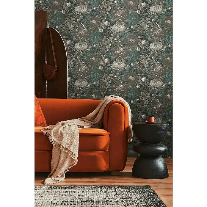 A.S. Création Michalsky Metropolis Vliestapete Blüten - Schwarz-Grau-Blau, Floral, 10,05 x 0,53 m - Elegantes Wohnzimmer mit orangefarbenem Sofa, gemusterter Tapete und dekorativem Beistelltisch.