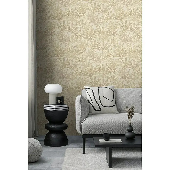 A.S. Création Michalsky Metropolis Vliestapete Hanfblätter - Creme-Beige, Floral, 10,05 x 0,53 m - Nahaufnahme eines Raumes mit einem stilvollen Sofa, einem Beistelltisch mit Lampe und einer auffälligen Tapete mit Blättermuster.