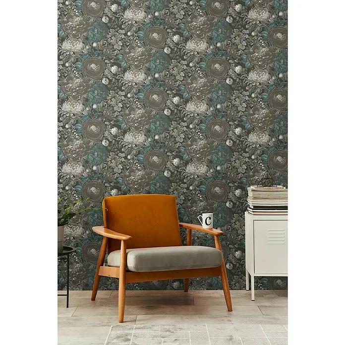 A.S. Création Michalsky Metropolis Vliestapete Blüten - Schwarz-Grau-Blau, Floral, 10,05 x 0,53 m - Zimmeransicht mit braunem Sessel, weißem Schrank und blumiger Tapete, die eine warme und einladende Atmosphäre schaffen.