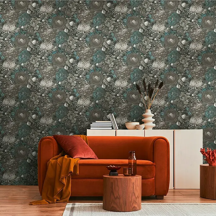 A.S. Création Michalsky Metropolis Vliestapete Blüten - Schwarz-Grau-Blau, Floral, 10,05 x 0,53 m - Wohnzimmer mit orangefarbenem Sofa, Holztischen und Blumenmustertapete.