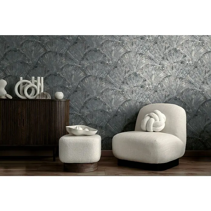 A.S. Création Metropolitan Stories Hot Spots Vliestapete Grafik - Blau-Grau-Metallic, Grafisch, 10,05 x 0,53 m - Elegantes Interieur mit einem bequemen Sessel mit einem Zierkissen, einem passenden Hocker und einem stilvollen Schrank vor einer gemusterten Wand.