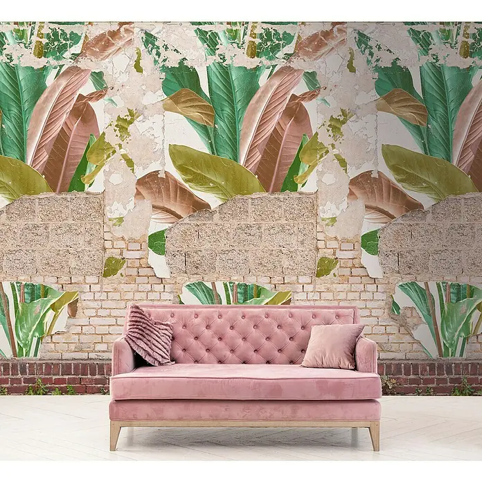 A.S. Création The Wall 2 Fototapete Steinwand Blätter - B x H: 159 x 280 cm, Vlies - Ein elegantes rosa Sofa mit gesteppter Rückenlehne steht vor einer Wand mit tropischen Blattmustern und freigelegtem Mauerwerk.