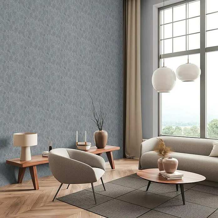A.S. Création Daniel Hechter 7 Vliestapete Blattdesign - Grau-Silber-Metallic, Floral, 10,05 x 0,53 m - Elegantes Wohnzimmer mit graublauer Tapete mit filigranem Blattmuster, ergänzt durch modernes Mobiliar und sanfte Farbnuancen für ein stilvolles Ambiente.