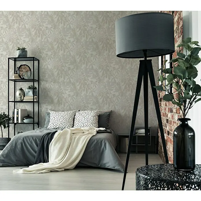 A.S. Création Daniel Hechter 7 Vliestapete Florale Schatten - Grau-Beige, Floral, 10,05 x 0,53 m - Elegantes Schlafzimmer mit einem modernen Dreibein-Stehlampe in Grau und einem dekorativen Beistelltisch mit Blumenvase.
