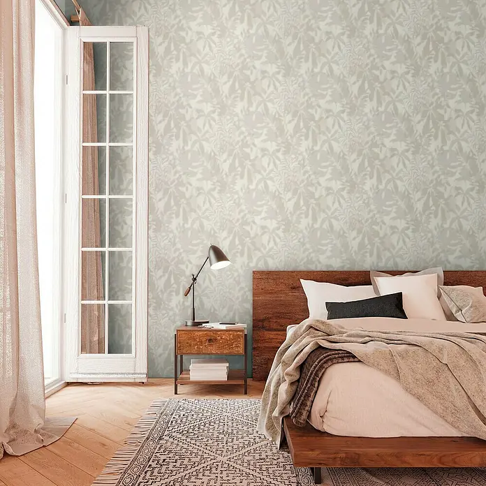 A.S. Création Daniel Hechter 7 Vliestapete Florale Schatten - Grau-Beige, Floral, 10,05 x 0,53 m - Schlafzimmer mit einem Holzbett, Nachttisch und einer floral gemusterten Tapete, die dem Raum eine gemütliche Atmosphäre verleiht.