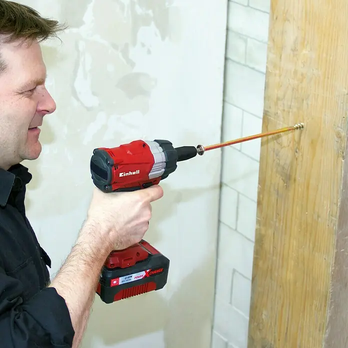 Einhell Professional Power X-Change 18V Akku-Impulsschrauber TE-CW 18 Li Brushless-Solo - 18 V, Ohne Akku, 215 Nm - Ein Mann schraubt mit einem Einhell Akku-Schlagschrauber eine Schraube in ein Holzbrett. Das Gerät ist rot und schwarz.