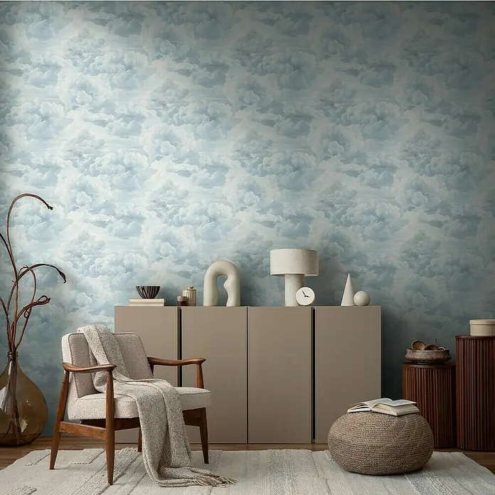 A.S. Création Michalsky Metropolis Vliestapete Wolken - Weiß-Blau, Sonstiges, 10,05 x 0,53 m - Ein Wohnzimmer mit bequemen Sessel und einem stilvollen Sideboard vor einer beruhigenden Wolkentapete.