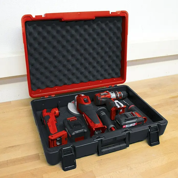 Einhell Werkzeugkoffer E-Box M55/40 - L x B x H: 400 x 550 x 150 mm, Kunststoff - Offener Werkzeugkoffer mit rotem Einhell-Akkuschrauber, Winkelschleifer, Multifunktionswerkzeug und Akkus auf einer Werkbank.