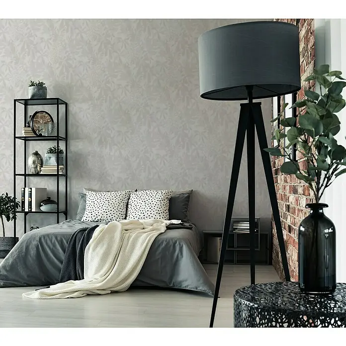 A.S. Création Daniel Hechter 7 Vliestapete Florale Schatten - Grau-Creme, Floral, 10,05 x 0,53 m - Schlafzimmer-Interieur mit einem modernen schwarzen Dreibein-Stehleuchte, das einen Hauch von Eleganz und Stil verleiht.