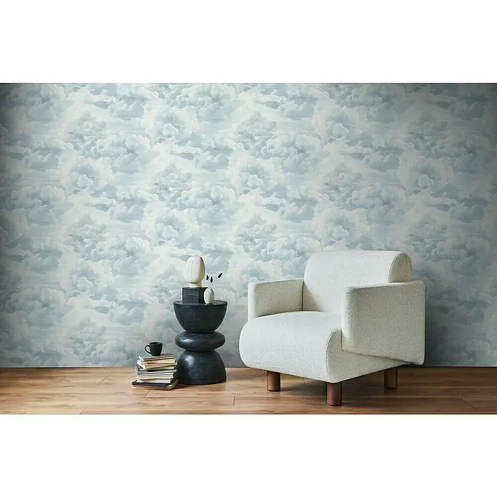 A.S. Création Michalsky Metropolis Vliestapete Wolken - Weiß-Blau, Sonstiges, 10,05 x 0,53 m - Elegantes Interieur mit einem beigen Sessel, einem Beistelltisch mit Deko und einer Wand mit Wolkenmuster, das eine ruhige Atmosphäre schafft.