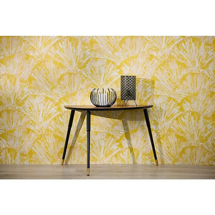 A.S. Création Metropolitan Stories Hot Spots Vliestapete Grafik - Gelb-Creme-Beige, Grafisch, 10,05 x 0,53 m - Ein stilvoller Tisch mit elegantem Design, dekoriert mit einer dekorativen Kerze und einer Lampe, vor einem auffälligen, gemusterten Hintergrund.