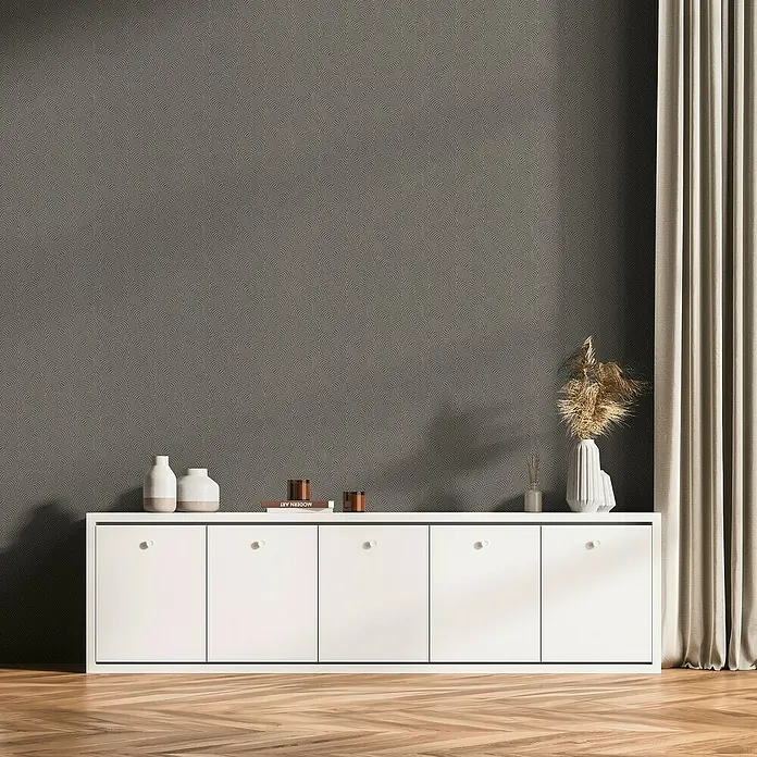 A.S. Création Daniel Hechter 7 Vliestapete 3D-Grafikstreifen - Grau-Metallic, Grafisch, 10,05 x 0,53 m - Das Bild zeigt eine weiße Kommode mit fünf Türen vor einer grauen Wand mit einem Muster. Auf der Kommode stehen Vasen und Dekorationsgegenstände.