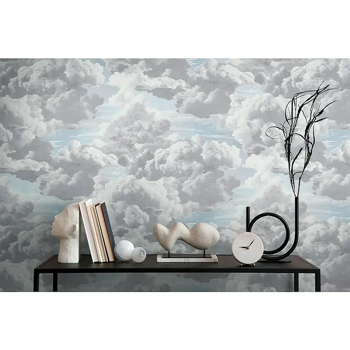 A.S. Création Michalsky Metropolis Vliestapete Wolken - Grau-Blau-Weiß, Sonstiges, 10,05 x 0,53 m - Deko-Arrangement auf einem schwarzen Tisch vor einer Wolken-Tapete. Skulpturen, Bücher und eine Uhr schaffen eine moderne Atmosphäre.