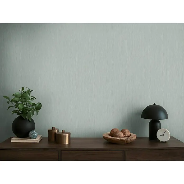 A.S. Création Michalsky Metropolis Vliestapete - Grau-Blau, Uni, 10,05 x 0,53 m - Stillleben mit Wohnaccessoires auf einem dunklen Holzschrank, darunter eine Lampe, eine Pflanze und dekorative Elemente.