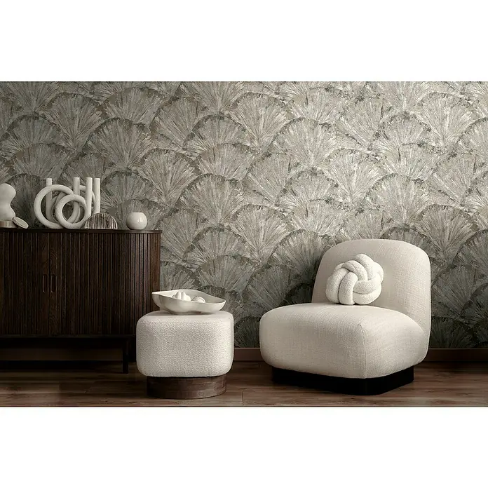 A.S. Création Metropolitan Stories Hot Spots Vliestapete Grafik - Beige-Braun-Metallic, Grafisch, 10,05 x 0,53 m - Elegantes Interieur mit einem cremefarbenen Sessel, einem passenden Hocker und einem dunklen Holzschrank vor einer gemusterten Wand.