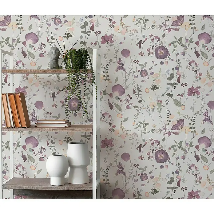 A.S. Création Pintwalls 2 Vliestapete Blumen - Violett-Grün-Gelb, Floral, 10,05 x 0,53 m - Nahaufnahme eines Bücherregals mit Dekoartikeln vor einer floralen Tapete, die das Regal und seine Produkte hervorhebt.