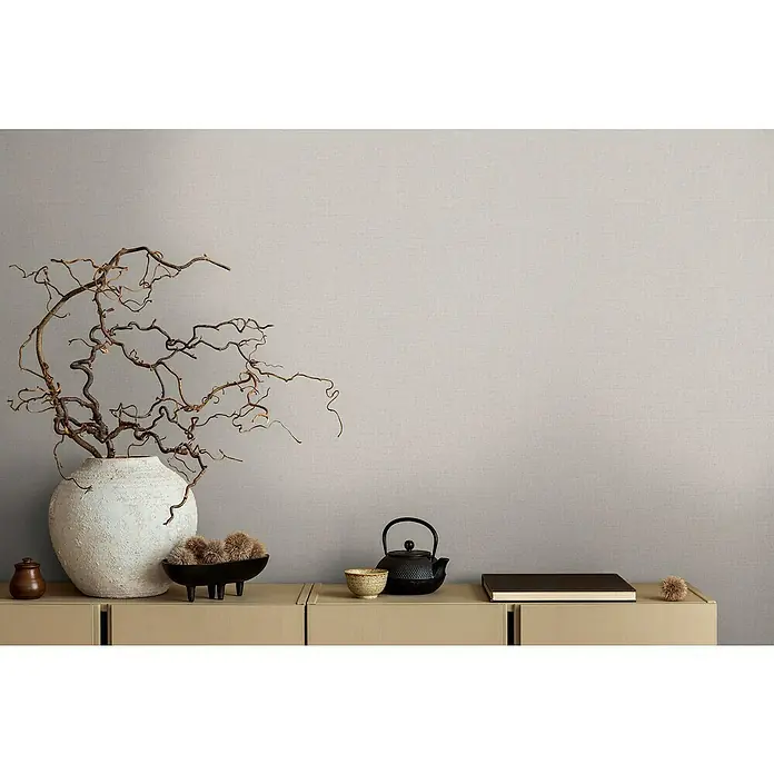 A.S. Création Michalsky Metropolis Vliestapete - Grau-Beige, Uni, 10,05 x 0,53 m - Einrichtungsgegenstände auf einem Sideboard: Vase mit Ästen, Schale, Teekanne und Buch für eine stilvolle Atmosphäre.