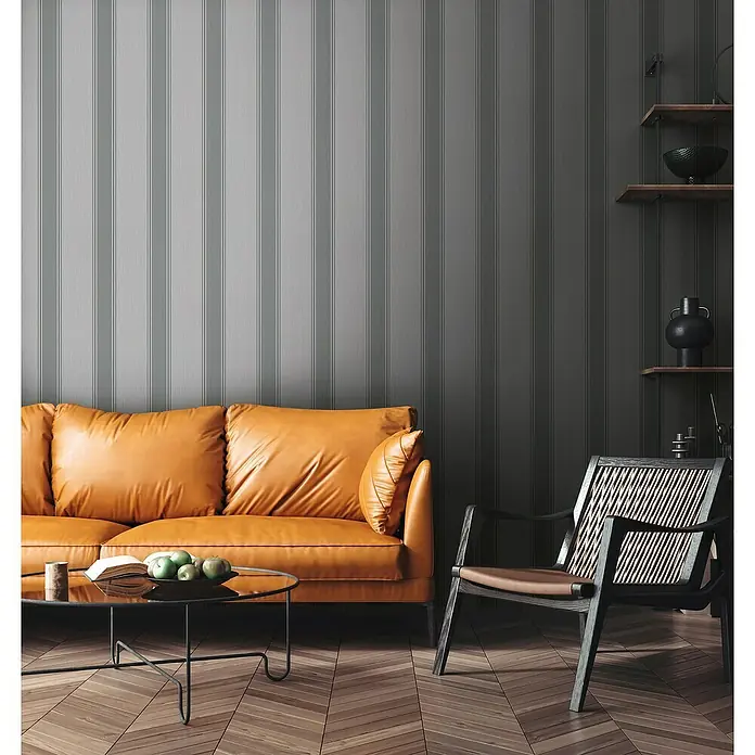 A.S. Création Michalsky Metropolis Vliestapete - Grau, Streifen, 10,05 x 0,53 m - Einladendes Wohnzimmer mit einem honigfarbenen Ledersofa, einem modernen Sessel und einem eleganten Couchtisch auf einem warmen Holzboden.