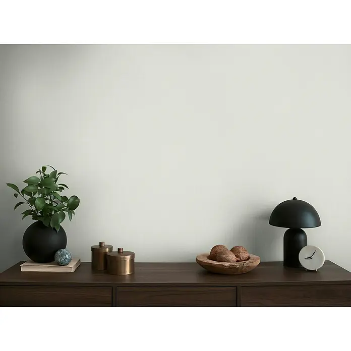 A.S. Création Michalsky Metropolis Vliestapete - Weiß-Grau, Uni, 10,05 x 0,53 m - Stillleben mit einer Zimmerpflanze, einer schwarzen Lampe, einer Holzschale mit Nüssen und dekorativen Accessoires auf einer Kommode.