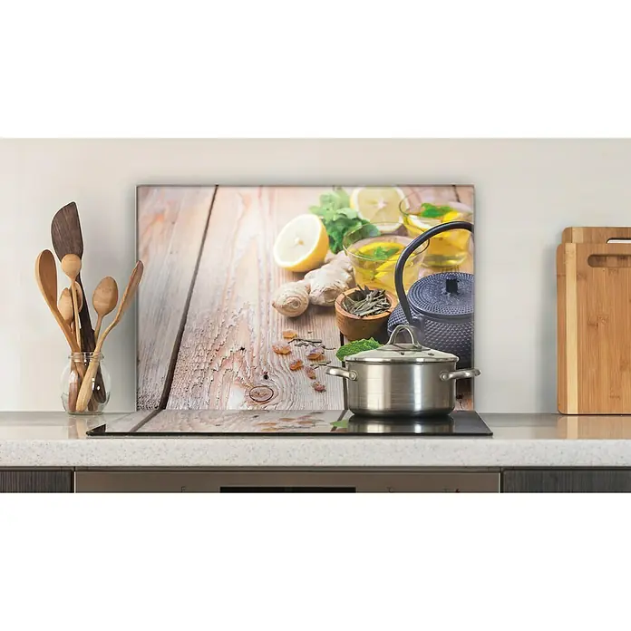 CUCINE Küchenrückwand - Ginger Tea, 60 x 40 cm, Stärke: 6 mm, Einscheibensicherheitsglas (ESG) - Küchenrückwand aus Glas mit Teemotiv. Die Glasplatte zeigt Zitrone, Ingwer und Kräuter auf einem Holztisch. Kochtopf steht auf dem Herd.