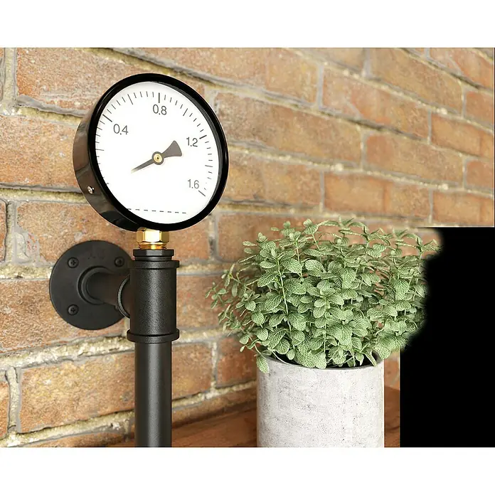 Walteco Rusticline Manometer - Stahl, Schwarz - Industrieller Manometer an Ziegelwand, neben einer Topfpflanze, zeigt einen Druckwert an.