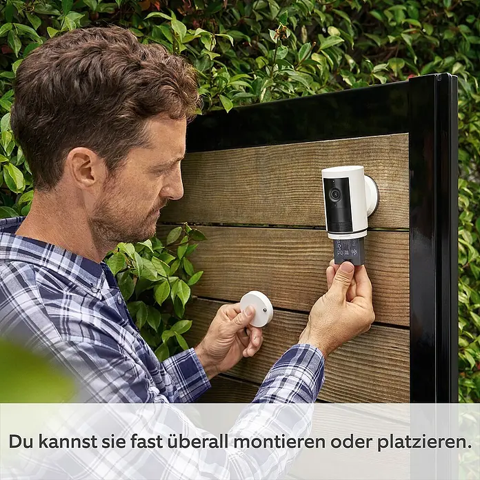 Ring Außenkamera Akku Plus - 2.048 x 1.536 Pixel (2K-HD), Schwarz - Ein Mann montiert eine Ring Stick Up Cam Battery an einer Holzwand. Einfache Installation fast überall im Innen- und Außenbereich.