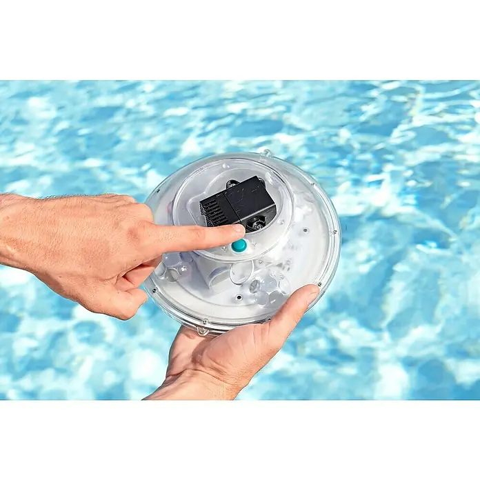 Bestway Sprinkler FloatBright™ - Transparent, Betriebsdauer: 3 h - Eine Nahaufnahme einer Person, die eine Poolleuchte vor dem Hintergrund eines Schwimmbads bedient.