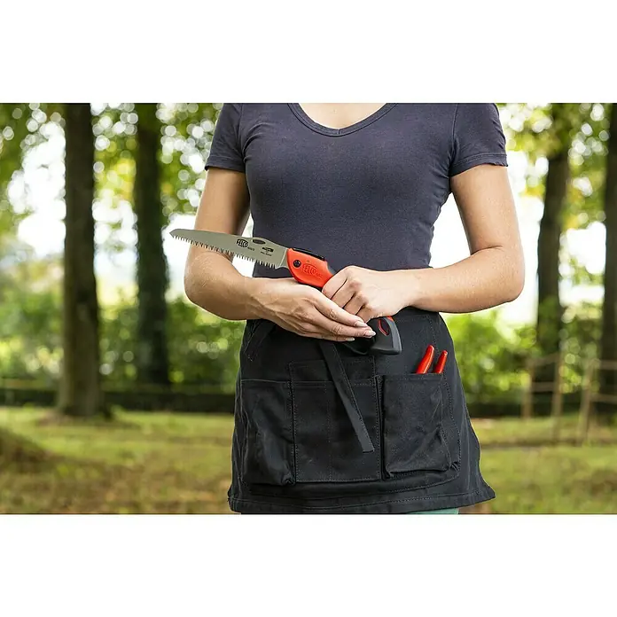 Felco Klappsäge 602 - Max. Aststärke: 80 mm - Nahaufnahme einer Frau mit einer FELCO-Zugsäge in der Hand, die eine schwarze Gartenschürze mit Werkzeugen trägt, im Freien.