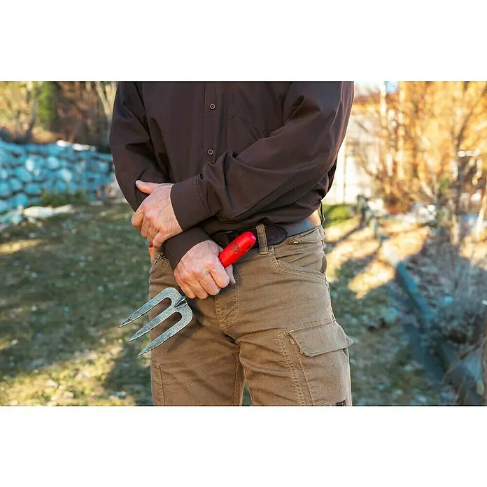 Felco Handgabel 431 - 33 cm - Nahaufnahme einer Person in braunem Hemd und Hose, die eine dreizinkige Gartenkralle in der Hand hält.