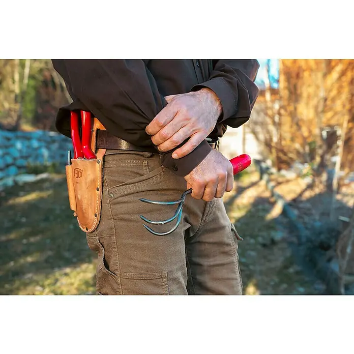 Felco Gartenkralle 411 - Arbeitsbreite: 5,5 cm - Nahaufnahme einer Person mit einer Gartenkralle in der Hand, ein Lederscheide mit Gartenschere am Gürtel und eine braune Jacke tragend.