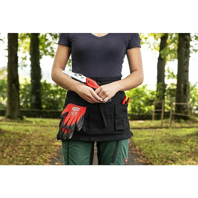 Felco Klappsäge 601 - Max. Aststärke: 60 mm - Eine Person trägt eine schwarze Gartenschürze mit Werkzeugen und Handschuhen, inklusive einer Felco-Säge, vor Bäumen.