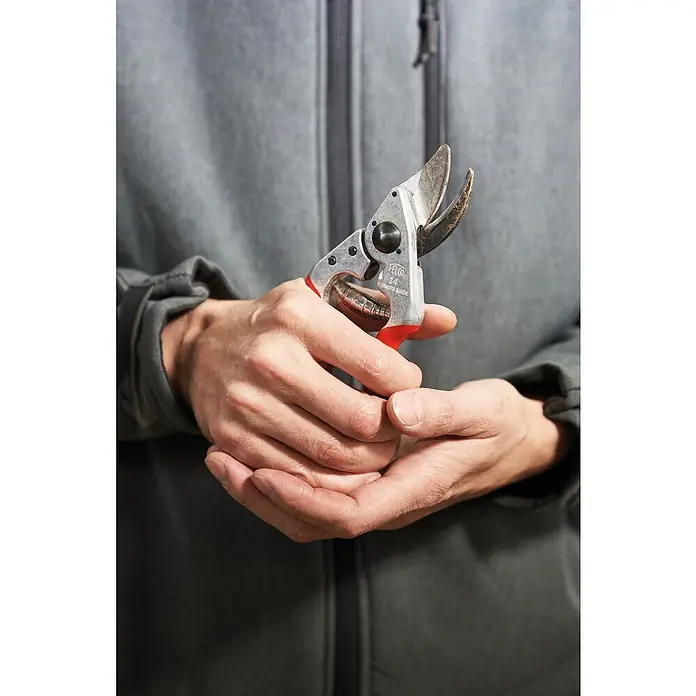 Felco Gartenschere 14 - Bypass, Max. Aststärke: 18 mm - Die Hände einer Person halten eine Felco 14 Gartenschere, ein Werkzeug zum Beschneiden und für die Gartenarbeit.
