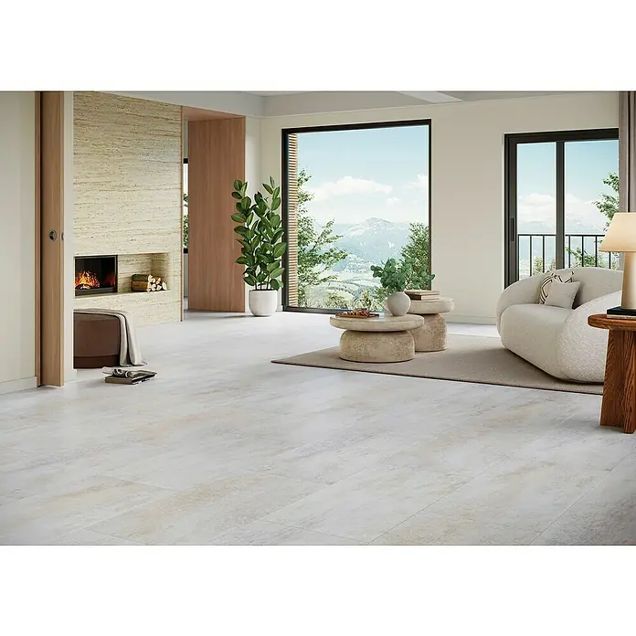 Parador Vinylboden Basic 5.3 - Dolomit weiß, Fliese, 914 x 457 x 5,3 mm - Das Bild zeigt einen hellen Raum mit Fliesenboden, einem Kamin und großen Fenstern mit Blick auf eine Berglandschaft.