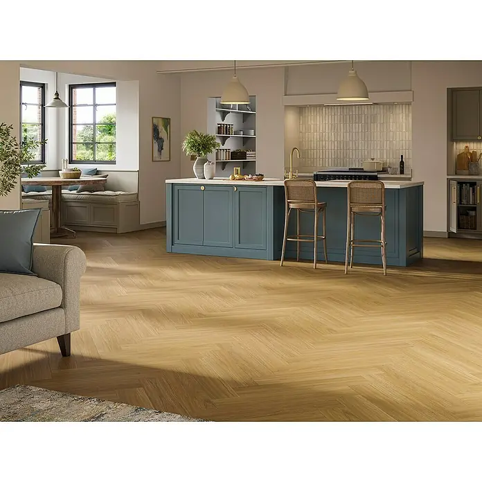 Parador Vinylboden Trendtime 3 - Eiche Oxford karamellbraun, Fischgrät, 730 x 146 x 5 mm - Einladender Raum mit Fischgrätparkett, blaugrüner Kücheninsel und bequemer Sitzecke. Die hellen Farben schaffen eine freundliche Atmosphäre.