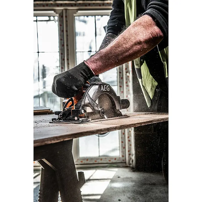 AEG Pro 18V Akku-Handkreissäge BKS 18SBL-0 - 18 V, Ohne Akku, 0 U/min - 5.000 U/min - Nahaufnahme einer AEG-Kreissäge in Aktion, bedient von einem Handwerker in Arbeitskleidung, um Holz präzise zu schneiden.\n