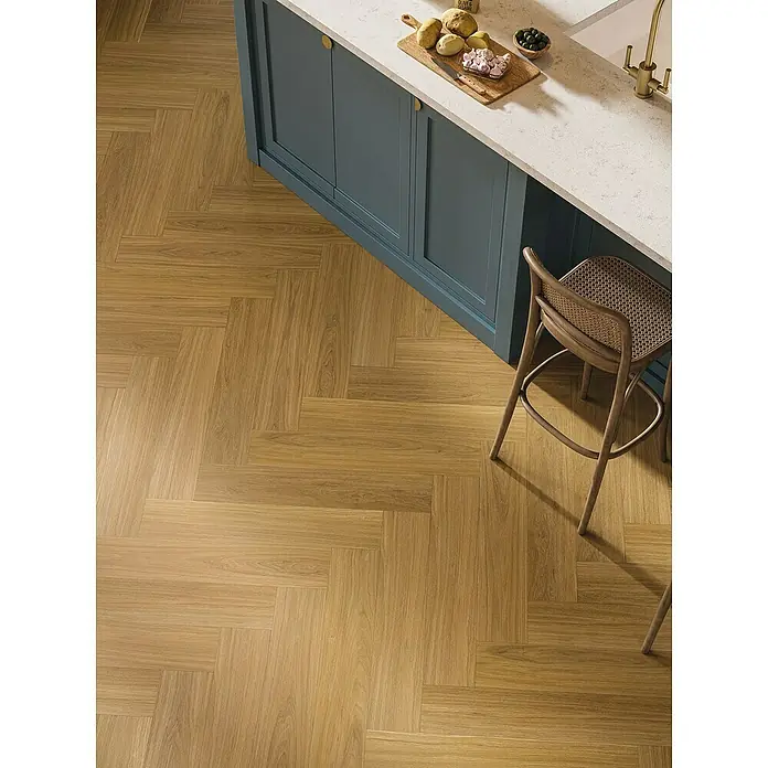 Parador Vinylboden Trendtime 3 - Eiche Oxford karamellbraun, Fischgrät, 730 x 146 x 5 mm - Nahaufnahme eines Küchenbodens mit Fischgrätmuster, der einen warmen Holzakzent in das Küchendesign bringt. Die hellen Holztöne ergänzen das Dekor.