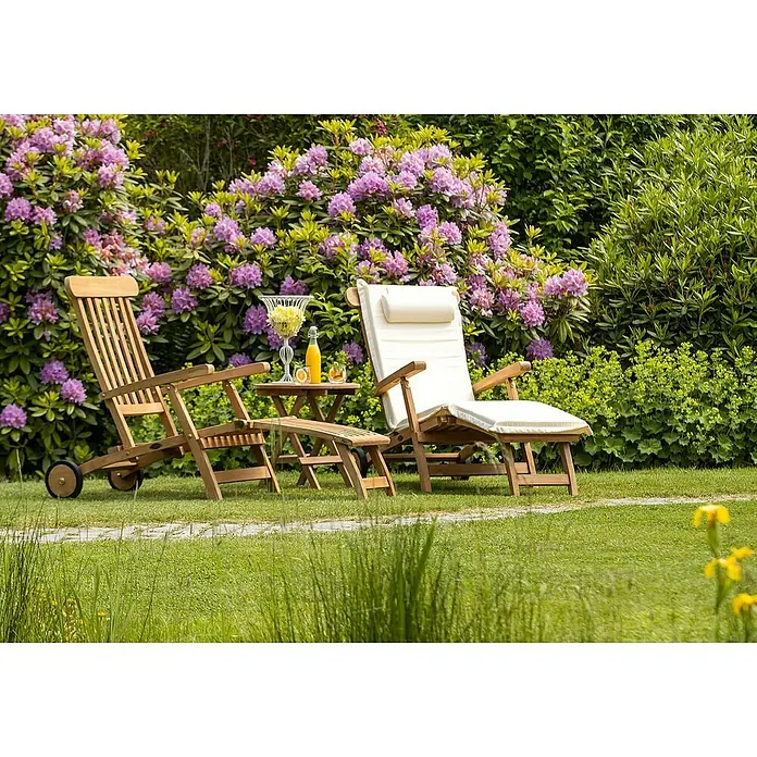 Kai Wiechmann Garten-Liegestuhl - Teak, Klappbar, Naturbelassen - Entspannen Sie auf diesen eleganten Holzliegen im Garten. Ein kleiner Tisch hält Erfrischungen bereit, umgeben von blühenden Blumen.