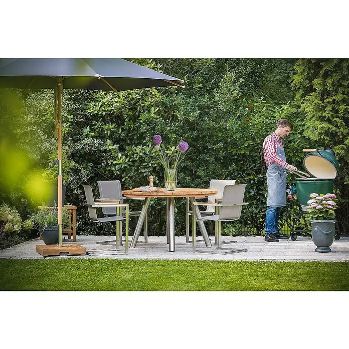 Kai Wiechmann Gartenstuhl - Stapelbar, Silber, B x T x H: 56 x 60 x 88 cm - Eine Szene im Freien mit einem Big Green Egg Grill, einem Tisch mit Stühlen und einem Sonnenschirm, umgeben von üppigem Grün.