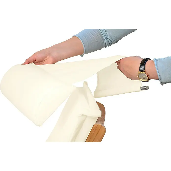 Kai Wiechmann Liegenauflage - Sonnenliege, Hochlehner, Relaxchair, L x B x H: 49 x 36 x 6 cm, Polyacryl, Naturweiß - Jemand legt einen creme-weißen Bezug über ein Massagegerät, wobei eine Armbanduhr am Handgelenk sichtbar ist.