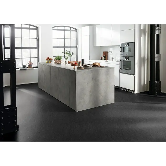 Egger Laminat Aquadura+ - Scivaro Schiefer, 1.292 x 327 x 7,5 mm - Moderne Küche mit einer großen Kochinsel in Betonoptik, die viel Arbeitsfläche bietet. Die dunklen Böden bilden einen schönen Kontrast zu den weißen Schränken.