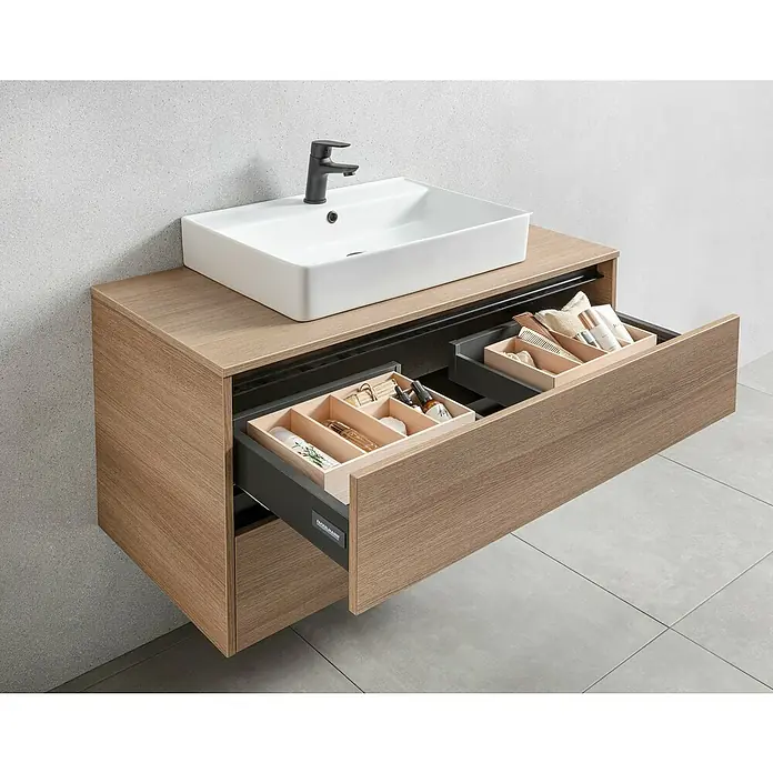 Fackelmann Vita Waschtischunterschrank - B x T x H: 100,4 x 46,5 x 51,6 cm, Summer Oak/Schwarz - Modernes Badezimmer mit Waschtischunterschrank aus Holz, offen Schubladen mit Kosmetikartikeln und weißes Waschbecken mit Armatur.