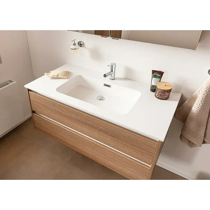 Fackelmann Vita Einbauwaschbecken - 101 x 46,5 cm, Hahnloch: Mitte, Mit Überlauf, Weiß - Waschtischunterschrank mit Schubladen, weißem Waschbecken und Armatur. Im Badezimmer mit Handtuch und Kosmetikartikeln.