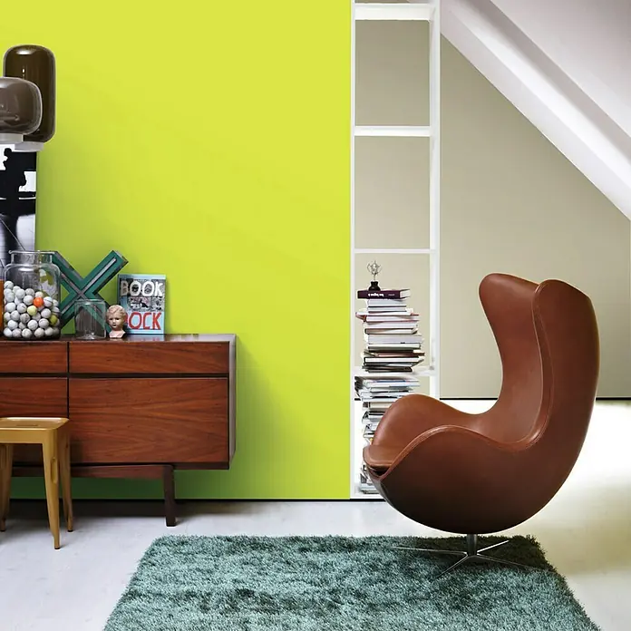 SCHÖNER WOHNEN-Farbe Wandfarbe Trendfarbe - Fresh, Matt, 2,5 l, Konservierungsmittelfrei - Einrichtung eines modernen Wohnzimmers mit braunem Egg Chair, Kommode aus dunklem Holz, Bücherregal und grüner Wand.