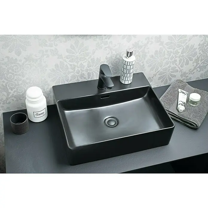 Fackelmann Aufsatzwaschbecken VAIDA - 50 x 42 cm, Hahnloch: Mitte, Mit Überlauf, Schwarz - Nahaufnahme eines stilvollen schwarzen Waschbeckens mit Armatur, Seifenspender und Handtuch auf einer modernen Badezimmeroberfläche.